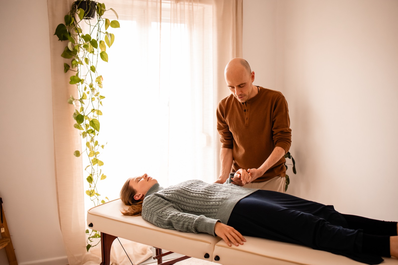 Dustin Laverick giving a craniosacral treatment in a calm, plant-filled room